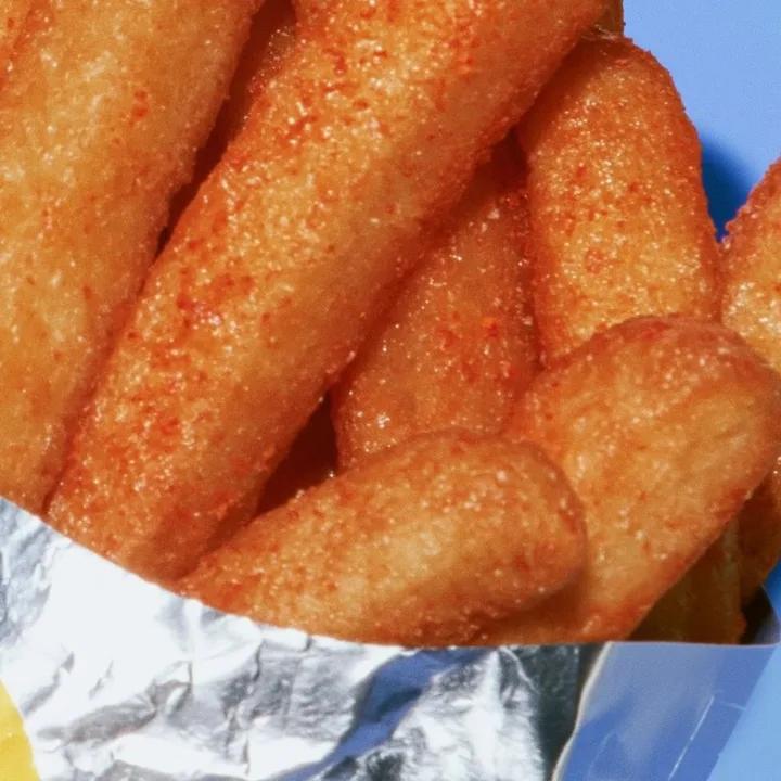 Ad: golden fries spilling from silver foil on blue